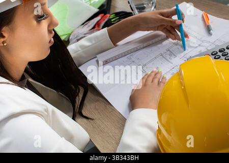 A Professional Female Engineer Actively Engaged in Creating and Analyzing Construction Plans Stock Photo