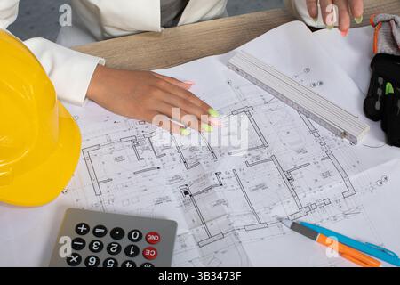 Professionals are thoroughly reviewing construction plans alongside tools and equipment arranged on a worktable Stock Photo