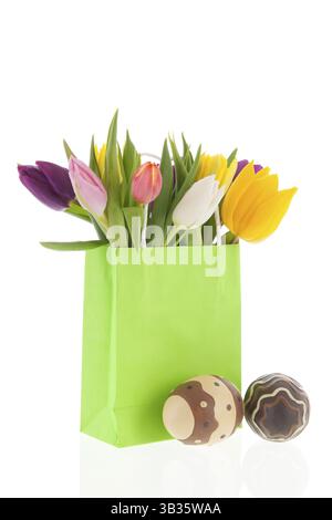 Paper shopping bag with colorful tulips in spring and chocolate easter eggs Stock Photo