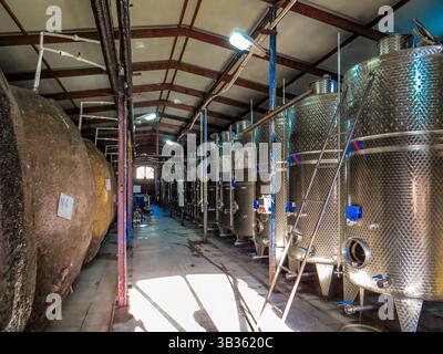 KVARELI, GEORGIA. Workers near fermentation tanks for wine production outdoors in yard of the plant Kindzmarauli Corporation Stock Photo