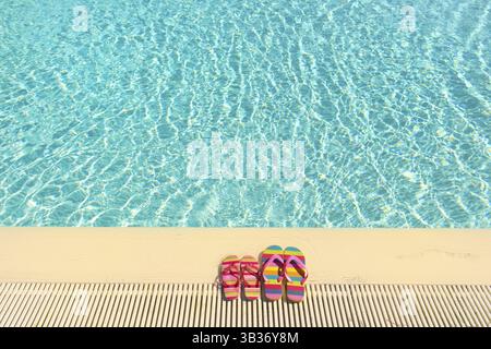 Colorful striped flip flops at swimming pool Stock Photo