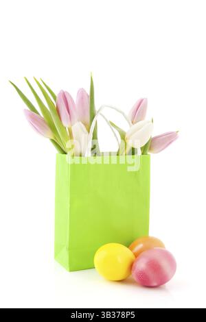 Colored easter eggs with bouquet tulips in green paper bag Stock Photo
