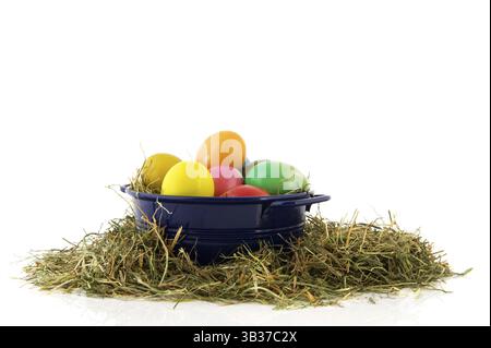 Blue bucket with straw and colorful painted easter eggs Stock Photo