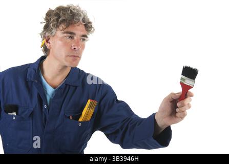 Handsome handyman in blue overall painting with red brush Stock Photo