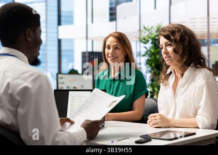 Cheerful HR managers asking interview questions to vet selected applicants and ensure their skills match role needs. Upbeat headhunters in company office assessing candidate work experience Stock Photo