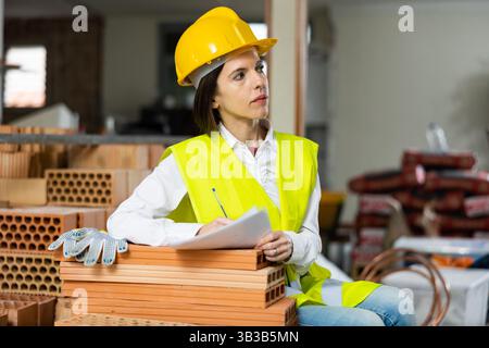 Female supervisor taking notes while inspecting construction site indoors Stock Photo