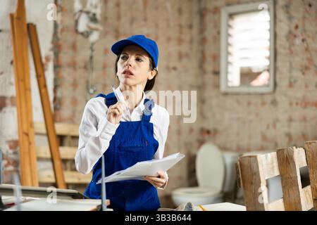 Female designer making checklist while planning building overhaul Stock Photo