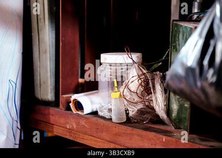 Messy workshop bench with tools, supplies, and tangled wires in a dusty setting Stock Photo
