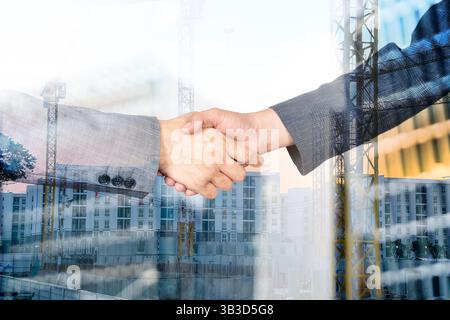 Two workers shaking hands on a construction site, business and industry theme. Men shaking hands in compliance and sealing a business contract for a t Stock Photo