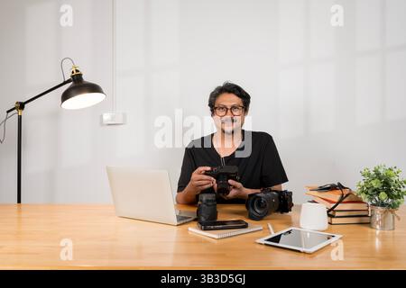 Adult bearded man indoors in cafe. Lifestyle concept photo with copy space. Picture with gray laptop, professional digital camera and aroma drink. Pho Stock Photo