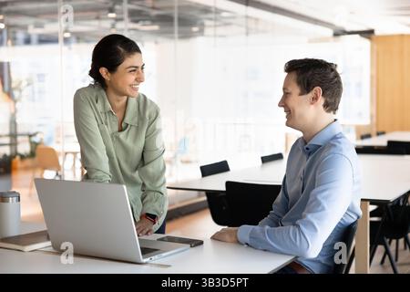 Two multiethnic colleagues engaged in funny conversation in co-working Stock Photo