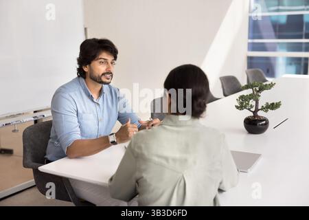 Teammates lead conversation about joint task seated at table Stock Photo