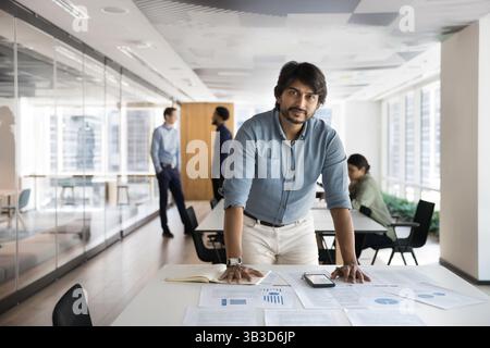 Portrait of Indian businessman standing at desk with financial documents Stock Photo