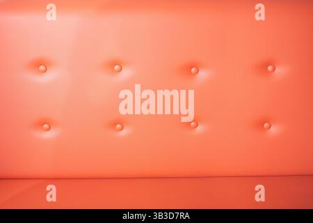 A view of the texture of a red orange pleather fabric sofa, as a background. Stock Photo