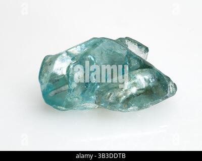 A close-up studio shot of a raw, translucent blue natural zircon crystal against a dark background showcasing its irregular facets and internal reflec Stock Photo