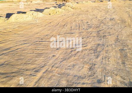 drone shot of excavated land surface with tracks aerial view of construction site ground and dirt piles Stock Photo