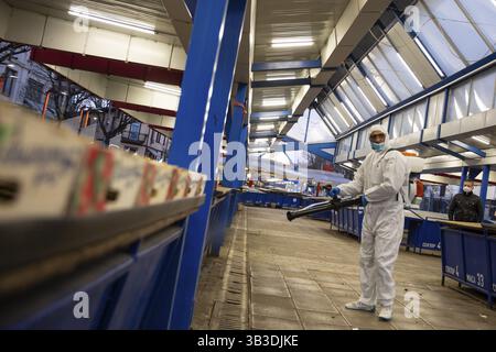 Sofia, Bulgaria - 7 April, 2020: Worker sprays disinfectant outside of Ð° food market against the spread of coronavirus disease COVID-19 Stock Photo