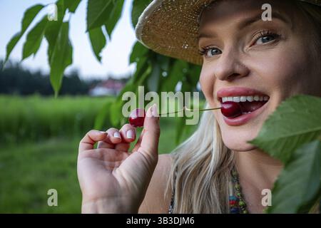 In the close-up shot, the woman's face and hands are the focal point. Her lips are painted and full, complementing her charming smile. With blue eyes Stock Photo