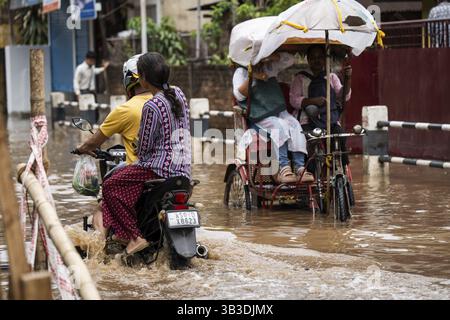 Commuters wade through a flooded street after heavy rains in Guwahati ...
