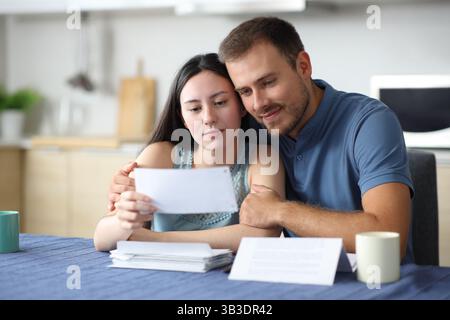 Satisfied interracial couple in love checking letter in the kitchen at home Stock Photo