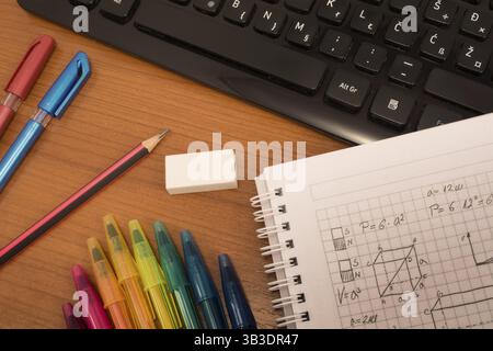 Computer keyboard, colorful pencils, eraser and notebook on the table Stock Photo