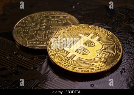 Virtual cryptocurrency money Bitcoin golden coins on a computer printed circuit board PCB. The future of money. Computational equipment. Dark image Stock Photo