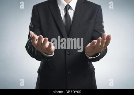 Businessman in black suit lending a helping hand, isolated on white background Stock Photo