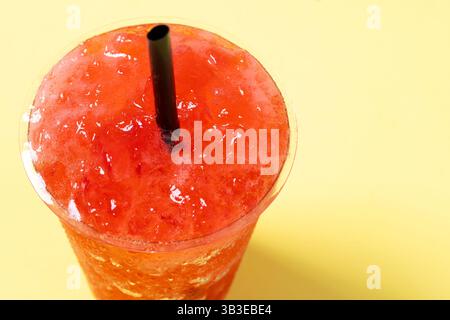 Red strawberry slushie isolated on yellow background. Stock Photo