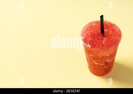 Red strawberry slushie isolated on yellow background. Stock Photo