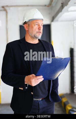 Professional engineer or foreman evaluating progress at work site, indoor setting. Stock Photo