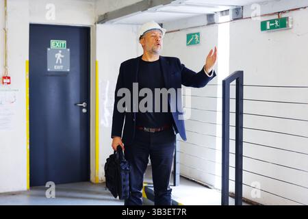 Construction manager in helmet giving directions on site. Safety and leadership concept Stock Photo