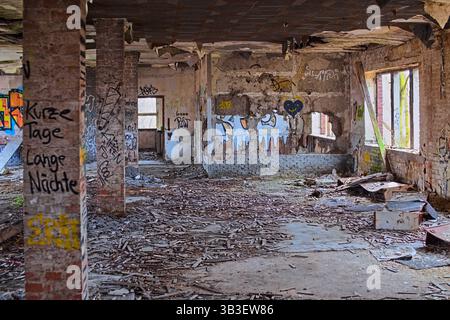 Abandoned brick interior filled with graffiti, fallen debris, and decaying structural walls. Stock Photo