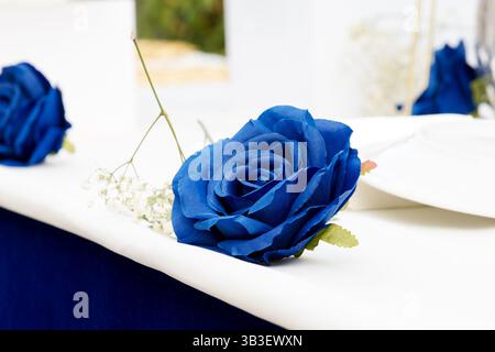 Handmade blue paper rose placed as a decorative centerpiece on a festive or wedding event table. Stock Photo