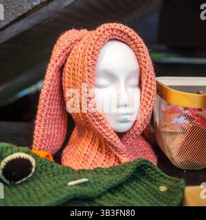 A knitted pink bunny hat with long ears is displayed on a white mannequin head. Stock Photo