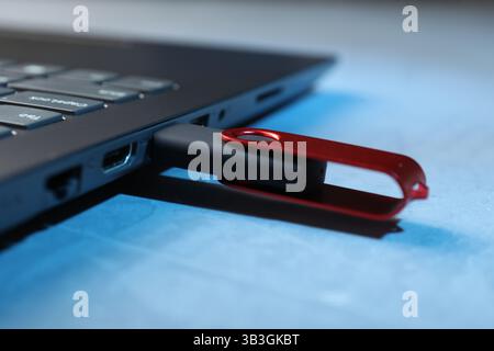 Usb flash drive connected to laptop on blue table, closeup Stock Photo