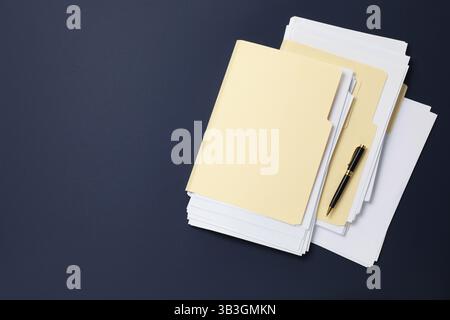 File folders with papers and pen on dark blue background, top view. Space for text Stock Photo