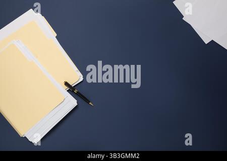 File folders with papers and pen on dark blue background, flat lay. Space for text Stock Photo