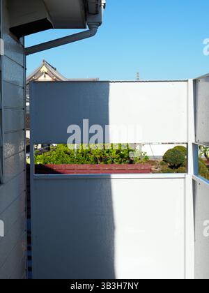 Morning light casting sharp shadows on a narrow balcony in a Japanese apartment Stock Photo