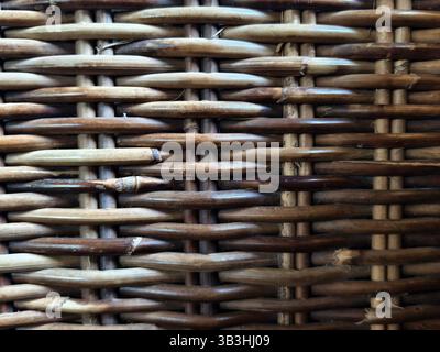 A close-up view of a woven rattan surface weaving pattern, showing the interlacing of natural materials Stock Photo