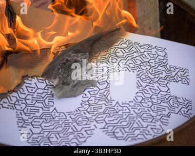 Bitcoin logo printed on paper burning in open flames — symbolic image representing cryptocurrency crash, data loss, digital currency volatility Stock Photo