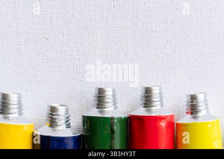 Small aluminum open tubes with acrylic paint on a white canvas Stock Photo