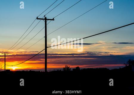 Power transmission line poles against the sky at sunset Stock Photo