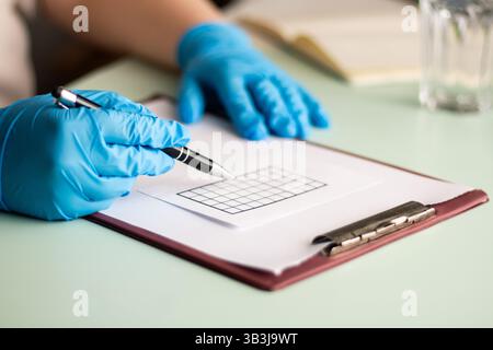 Doctor or physician in blue gloves writing diagnosis and think trough treatment plan and medication intake. Close up Stock Photo