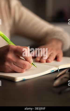 Close up image of human holding pen and writing something on blank white page in notebook Stock Photo