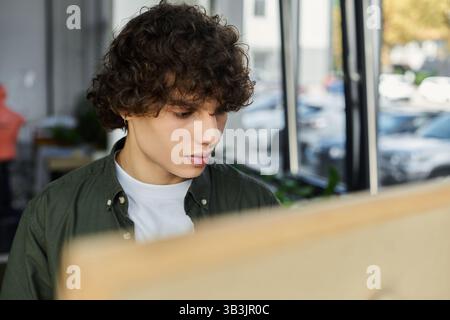 A young person focused on work in a bright, modern office. Stock Photo