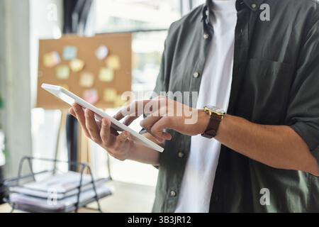 A person interacts with a tablet in a bright office space, showcasing dedication to efficient work. Stock Photo