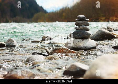 a seething mountain river with large stones, the stones are stacked in a pyramid in the middle of the stream, concept of balance and harmony Stock Photo