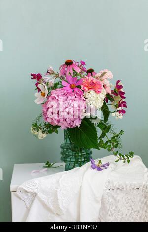 A bouquet of summer flowers in the room. Hydrangea, rose, echinacea, mint, snapdragon, asparagus and other flowers. Stock Photo