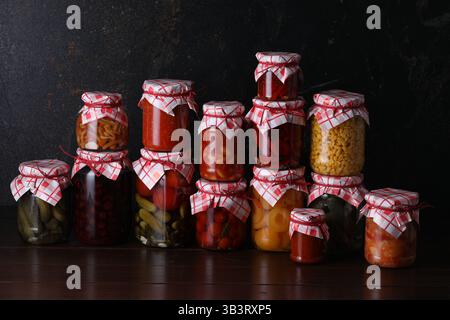 Many jars with different pickled products on wooden table Stock Photo