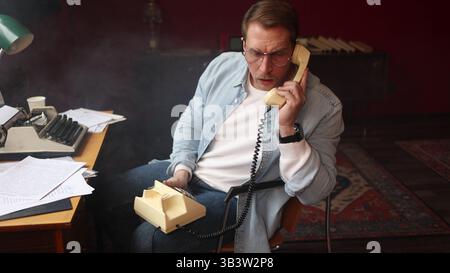 Author in cinematic vintage office, on phone with typewriter and papers in soft-focus composition. Stock Photo